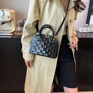 Modische schwarze Lackleder-Muscheltasche mit Webstruktur und goldenen Metalldetails