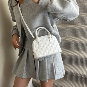 Weiße Muscheltasche mit gesteppter Textur am Modell für einen modernen Mode-Look