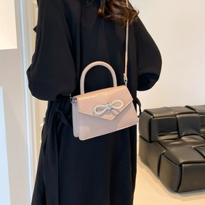 Sac à main rose à motif crocodile avec nœud en strass porté par un mannequin