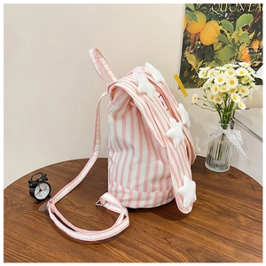 Detail of pink striped canvas backpack with rabbit ears and plush stars on wooden table