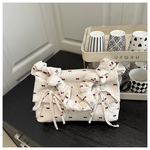 Close-up of floral canvas bag featuring red bow patterns and pleated drawstring details