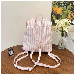 Detail of pink and white striped canvas backpack on a wooden table with home decor