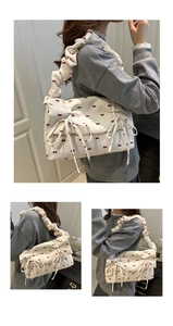 Detail der weißen Stofftasche mit roten Schleifenmustern und plissiertem Trageriemen