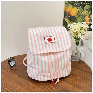 Close-up of pink striped canvas backpack with apple embroidery on a wooden table
