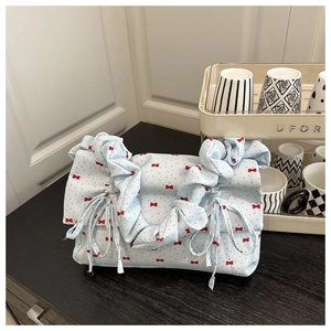 Detail of light blue pleated handbag featuring red mini bows and a ruffled cloud handle