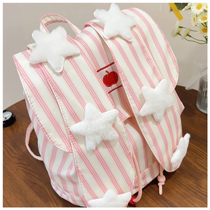 Close-up of pink striped backpack featuring plush white star charms and apple patch