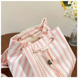 Detail of pink striped canvas backpack featuring drawstring closure and metal magnetic buckle