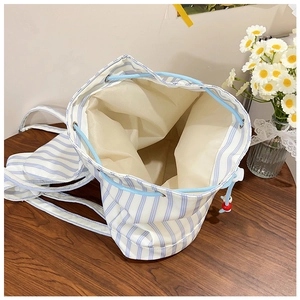 Detail of blue and white striped canvas drawstring backpack on a rustic wooden table