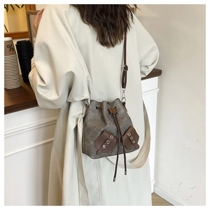 Detail of retro bucket bag in grey canvas with brown leather accents and eyelet trim