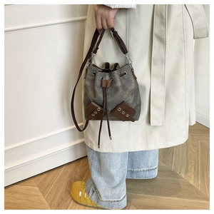 Close-up of retro grey canvas bucket bag with brown leather trim held by model