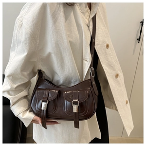 Detail of dark brown faux leather bag with dual front pockets and silver metal buckles