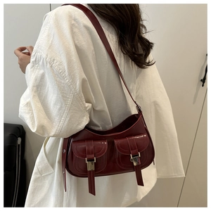 Detail of burgundy glossy leather shoulder bag with vintage buckles and pockets