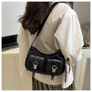 Detail of a black glossy leather hobo bag with front cargo pockets on a casual model