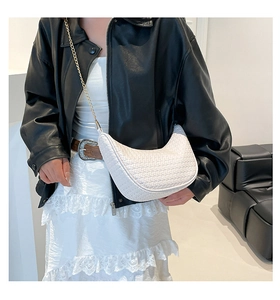 Détail du sac demi-lune blanc tressé avec chaîne dorée sur mannequin en veste en cuir