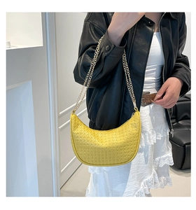 Détail du sac croissant jaune tissé avec chaîne dorée sur un mannequin élégant
