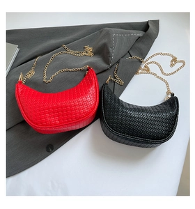 Detail of red and black woven crescent bags with gold chain straps on fabric