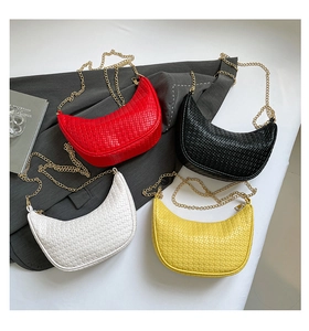 Vue détaillée de sacs demi-lune tissés en rouge, noir, blanc et jaune avec chaînes dorées