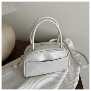 Close-up of cream Boston handbag with gold hardware and removable strap on fabric
