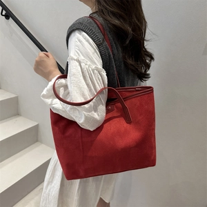 Red suede tote bag with contrast stitching and shoulder strap shown on a model
