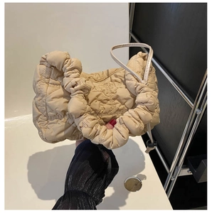 Detailed view of beige quilted handbag featuring plush cloud handle and drawstrings