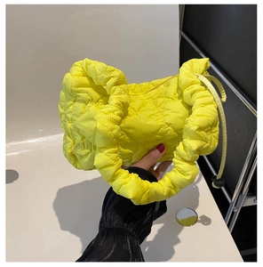 Detailed view of yellow quilted nylon cloud bag featuring soft padded texture and handles