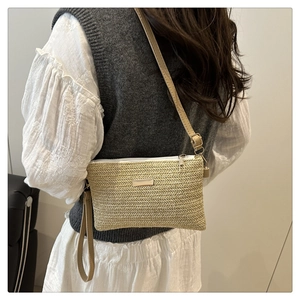 Detail of natural straw crossbody bag with V-shaped weave and gold metal plate detail