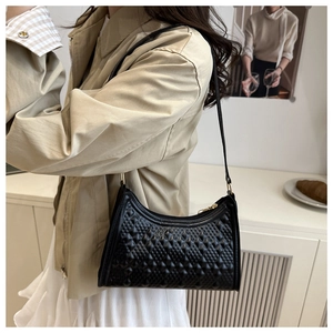 Detailed close-up of minimalist black baguette bag with embossed diamond lattice texture