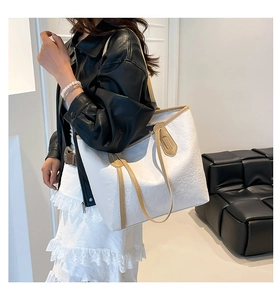 Detail of white tote bag with embossed heart patterns and tan leather trim on model