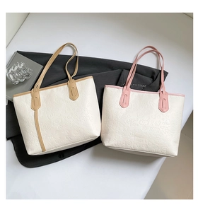Detail of cartoon embossed tote bag with contrast handles in camel and pink colors