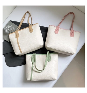 Detailed view of three white tote bags with colorful handles and full-surface floral embossing