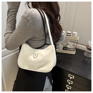 Detail of white half-moon shoulder bag with a crystal-encrusted heart bow metal logo