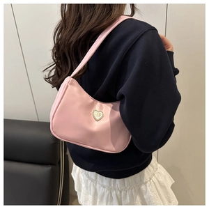 Detail shot of pale pink crescent hobo bag with heart buckle worn on shoulder