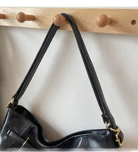 Detail of vintage black leather tote showing the narrow shoulder strap and gold metal hardware