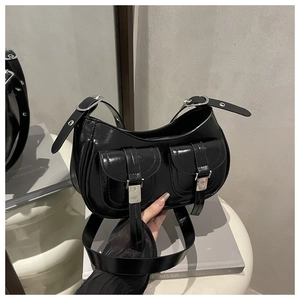 Detail of black glossy faux leather hobo bag with silver buckle pockets and moto style