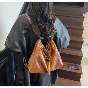 Close-up of retro brown leather backpack worn on shoulder with textured finish