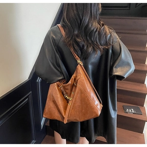 Detail shot of a dark brown hobo shoulder bag with smooth leather texture and metal buckle