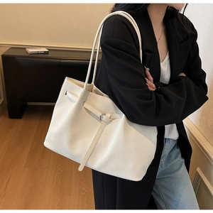 Detailed view of white textured leather tote bag worn with a black blazer outfit