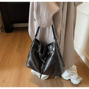 Detail of vintage black faux leather tote bag with gold metallic buckle and textured finish