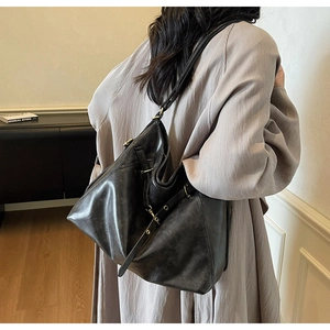 Close-up of black matte leather tote bag with adjustable metal eyelet shoulder strap