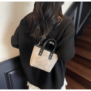 Detailansicht der beige-schwarzen Beuteltasche mit goldenen Details am Model