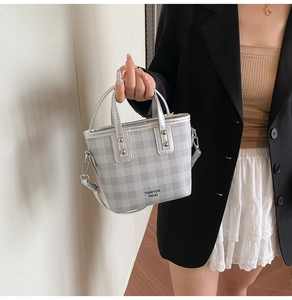 Detail of silver checkered bucket bag with metal hooks and logo on high-quality leather