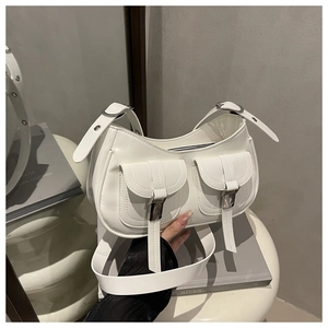 Detail view of white polished PU leather shoulder bag with silver buckle and dual front pockets