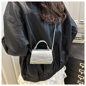 Détail du mini sac bandoulière argenté à motif crocodile avec rabat ondulé et anse