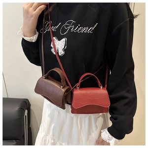 Close-up of mini crocodile pattern handbags in red and brown with fine shoulder straps