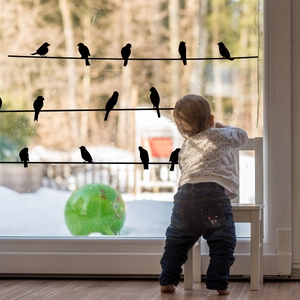Decorative black bird silhouette static window stickers on glass overlooking snowy yard