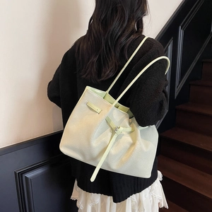 Elegante borsa tote intrecciata verde chiaro con manici lunghi mostrata da una modella