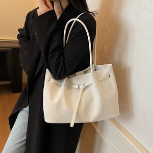 Elegante borsa tote in pelle bianca con trama diagonale e manici lunghi su cappotto nero