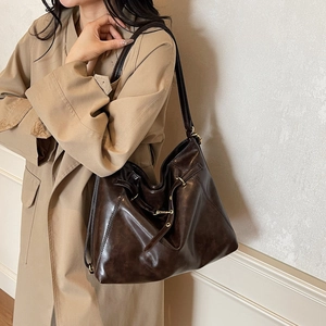 Classic dark brown leather tote bag worn over the shoulder with a stylish khaki trench coat