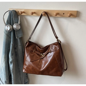 Detail of dark brown tote bag hanging on wooden hook with urban lifestyle accessories
