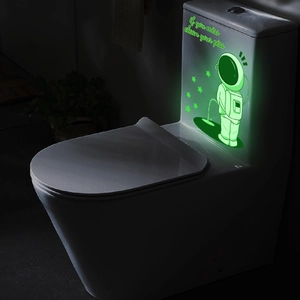 Glow-in-the-dark astronaut decal on toilet tank showing fluorescent light in dark bathroom